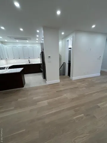 a view of a large kitchen with kitchen island a sink wooden floor and a counter top space