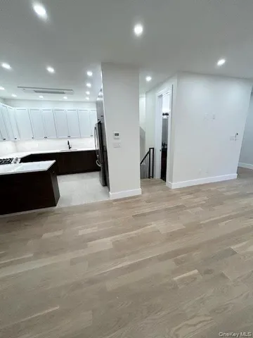 a kitchen with stainless steel appliances granite countertop a sink a stove a refrigerator and white cabinets