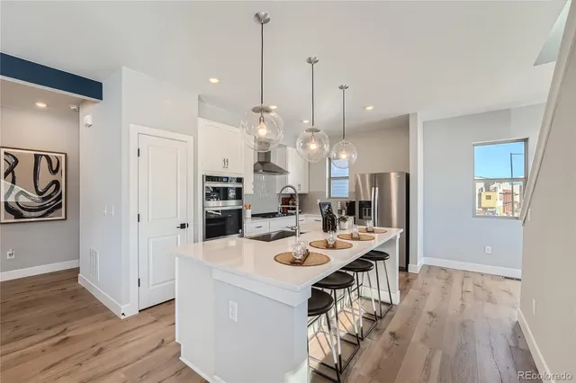 a view of a kitchen with kitchen island wooden floor center island and stainless steel appliances