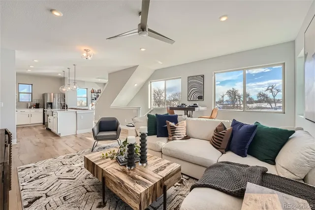 a living room with furniture kitchen view and a wooden floor