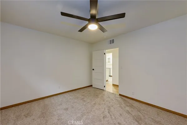 an empty room with chandelier fan and windows