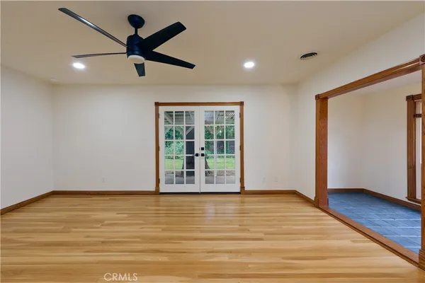 a view of empty room with wooden floor and fan