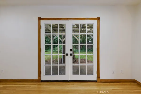 a view of an empty room with wooden floor and a ceiling fan