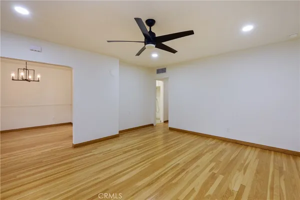 a view of empty room with wooden floor and fan