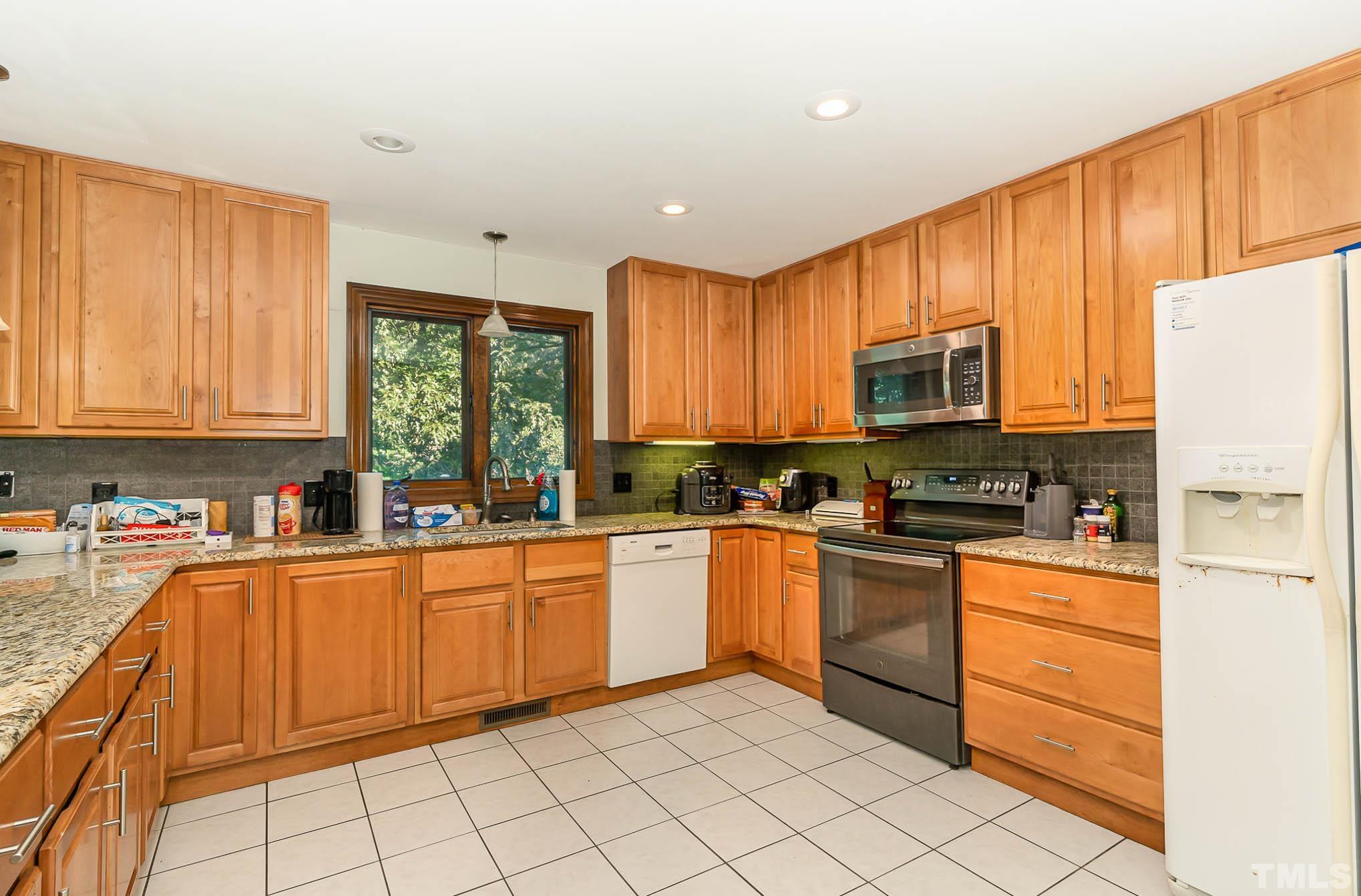 8700 Stage Ford Road Raleigh, NC 27615 - Photo 14 of 25 a kitchen with stainless steel appliances granite countertop a stove top oven a sink dishwasher and a refrigerator with wooden cabinets
