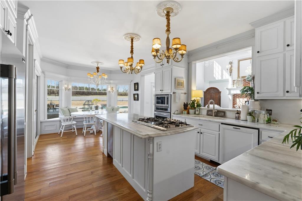 31 Duck Pond Road Roopville, GA 30170 - Photo 46 of 136 a kitchen with stainless steel appliances granite countertop a stove top oven a sink a dining table and chairs with wooden floor