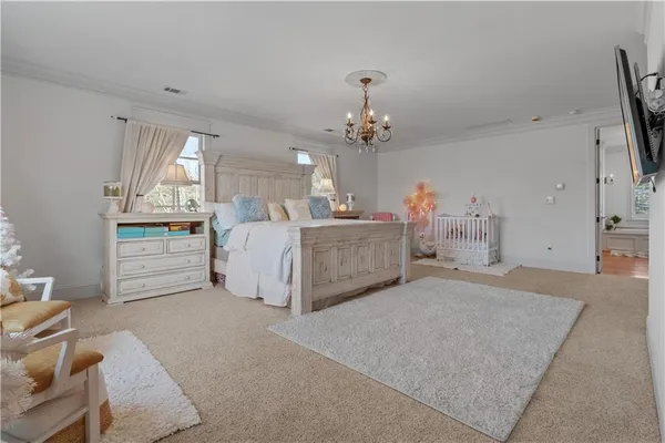 a bedroom with a large bed a flat tv screen and a dresser