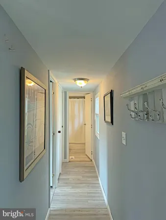 a view of a hallway with wooden floor and cabinet