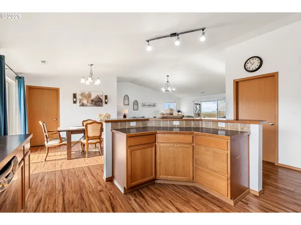 a open kitchen with stainless steel appliances granite countertop a refrigerator a sink dishwasher a dining table and chairs with wooden floor