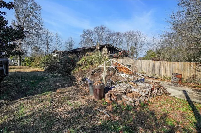 a view of a yard with large trees and wooden fence
