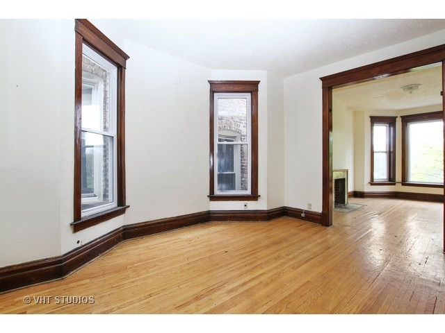 6045 South Peoria Street Chicago, IL 60621 - Photo 2 of 10 a view of an empty room with wooden floor and a window