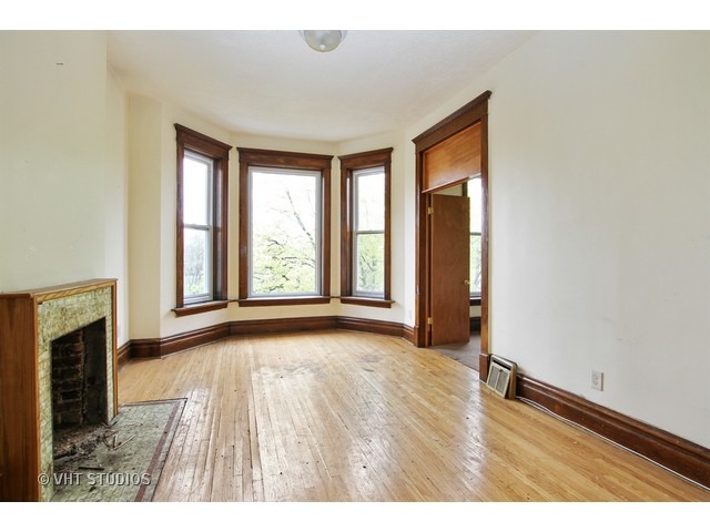 6045 South Peoria Street Chicago, IL 60621 - Photo 3 of 10 an empty room with wooden floor and windows