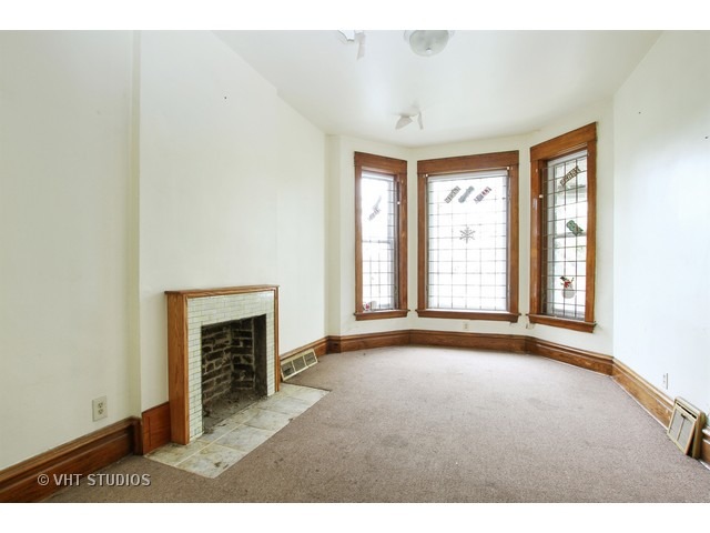 6045 South Peoria Street Chicago, IL 60621 - Photo 4 of 10 a view of an empty room with a fireplace and a window
