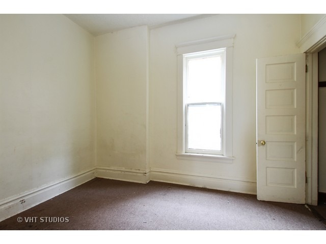6045 South Peoria Street Chicago, IL 60621 - Photo 9 of 10 an empty room with wooden floor and windows