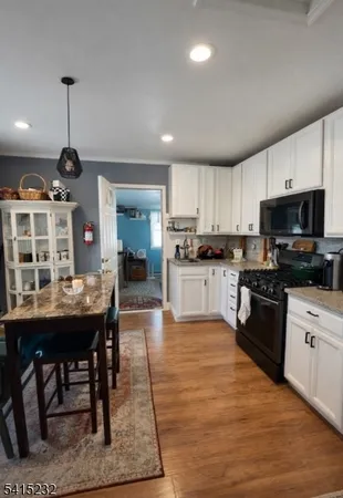 a kitchen with stainless steel appliances granite countertop a stove top oven a sink a dining table and chairs with wooden floor