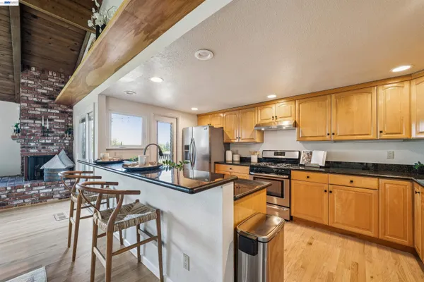 a kitchen with stainless steel appliances granite countertop a stove top oven a sink dishwasher and cabinets with wooden floor