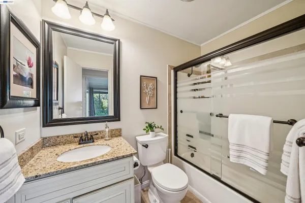 a bathroom with a granite countertop sink toilet a mirror and shower