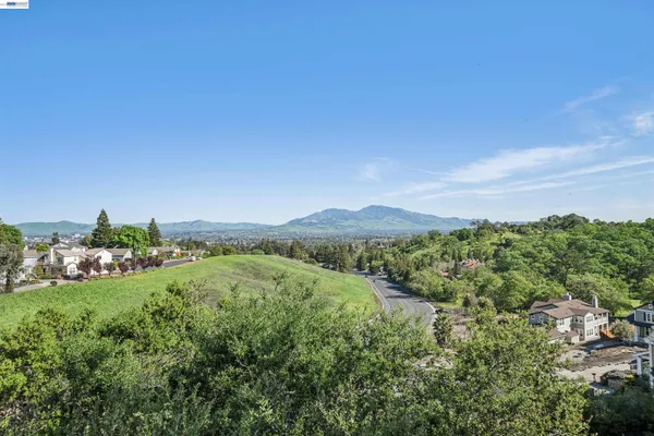 a view of a lush green outdoor space with a swimming pool and valleys in the background