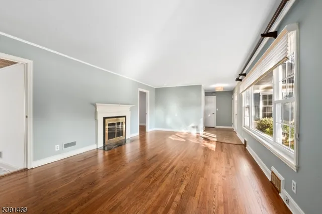 a view of empty room with wooden floor and fireplace