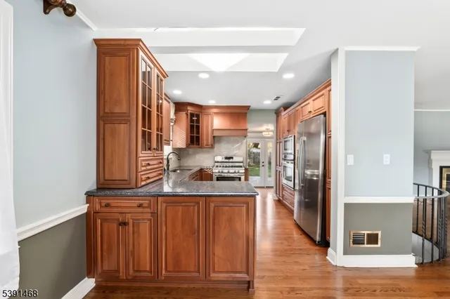 a kitchen with stainless steel appliances granite countertop a refrigerator a stove and a sink