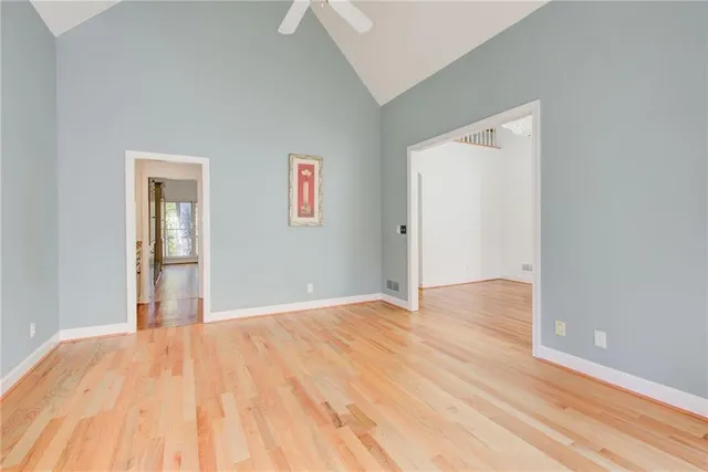 a view of an empty room with wooden floor fireplace and a window