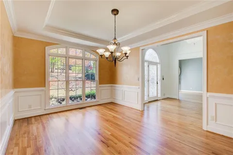 a view of a livingroom with wooden floor a ceiling fan and windows
