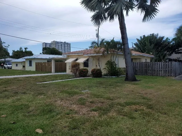 a view of a house with a yard and palm tree