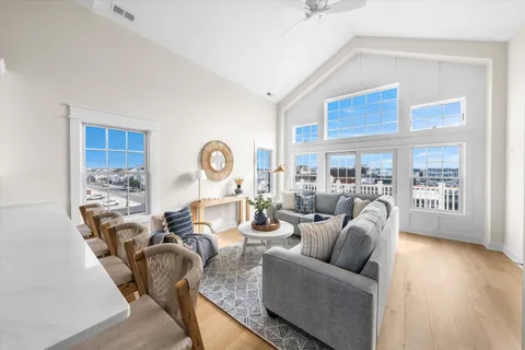 a living room with couches a coffee table and kitchen view with wooden floor