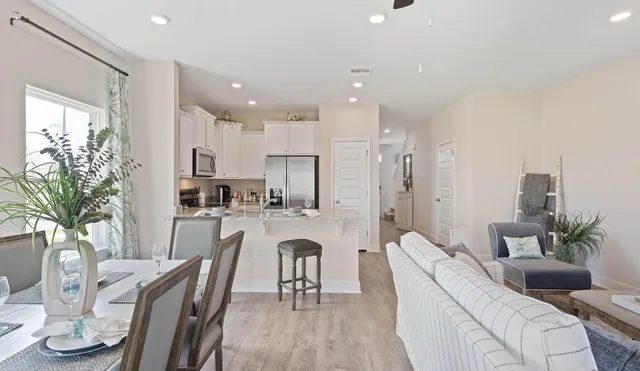 a living room with furniture kitchen view and a large window