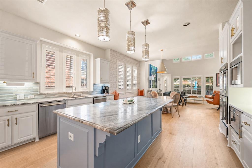 1521 Newton Ranch Road Keller, TX 76248 - Photo 13 of 40 Spacious kitchen featuring an expansive center island with marble countertop, light wood-finish flooring, white cabinetry with gold-tone hardware, and integrated Thermador stainless steel appliances
