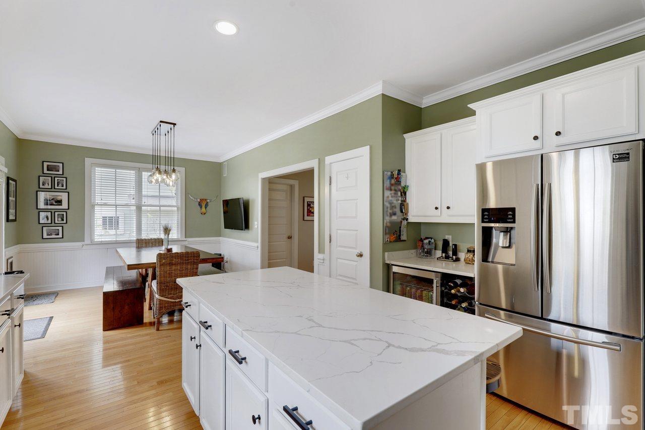 121 East Seeman Street Durham, NC 27701 - Photo 11 of 31 a kitchen with a refrigerator a stove and white cabinets with wooden floor