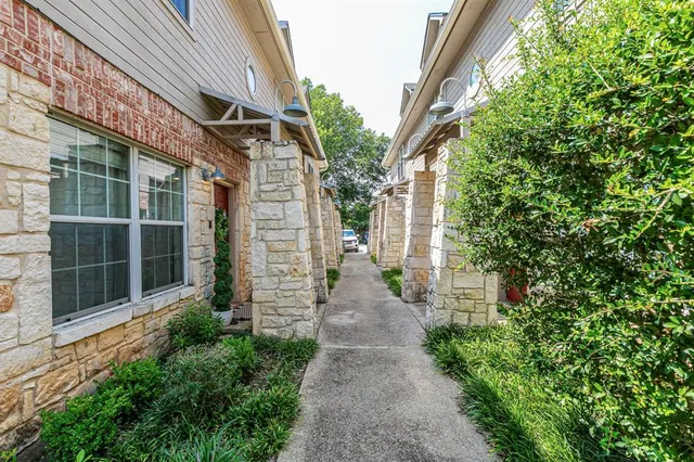 a view of a pathway of a house with a large window and plants