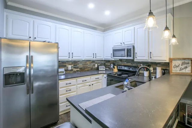 a kitchen with stainless steel appliances granite countertop a refrigerator a stove a sink a dining table and chairs with wooden floor