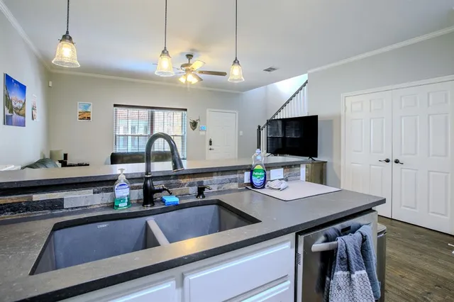 a kitchen with stainless steel appliances a sink dishwasher a stove top oven a dining table and chairs with wooden floor