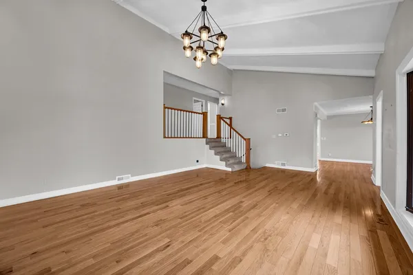 a view of an empty room with window and wooden floor