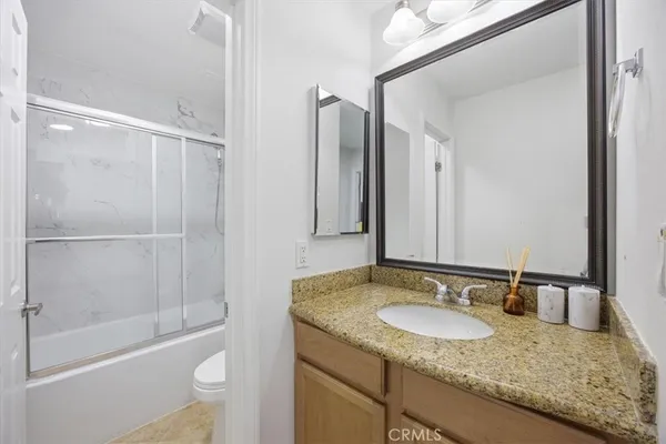 a bathroom with a granite countertop sink and mirror with bathtub
