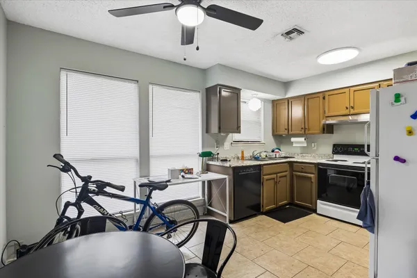 a kitchen with stainless steel appliances granite countertop a stove top oven a sink dishwasher a dining table and chairs with wooden floor
