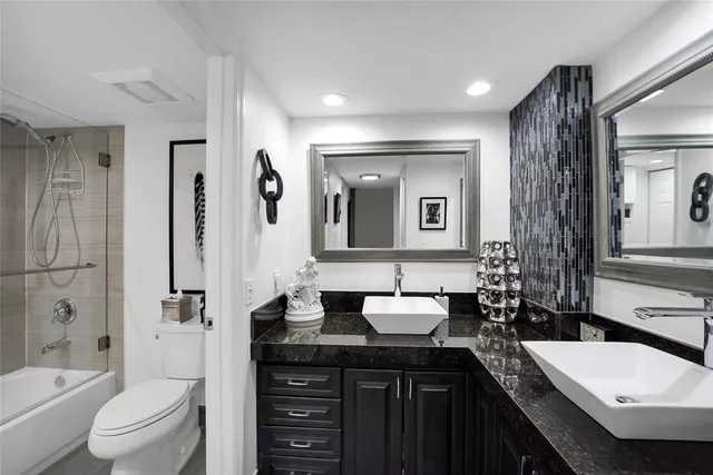 a bathroom with a double vanity sink toilet mirror and bathtub