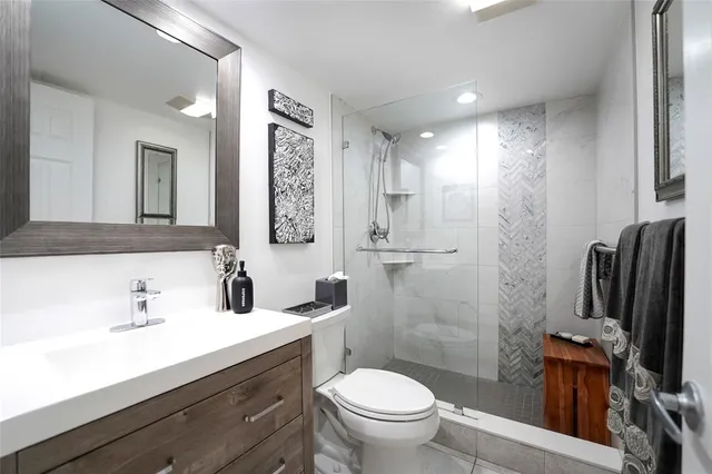 a bathroom with a sink a toilet a mirror and shower