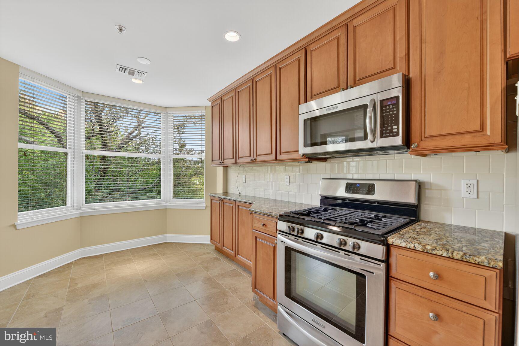 11776 Stratford House Place, Unit 507 Reston, VA 20190 - Photo 15 of 40 a kitchen with granite countertop wooden cabinets stainless steel appliances and a window