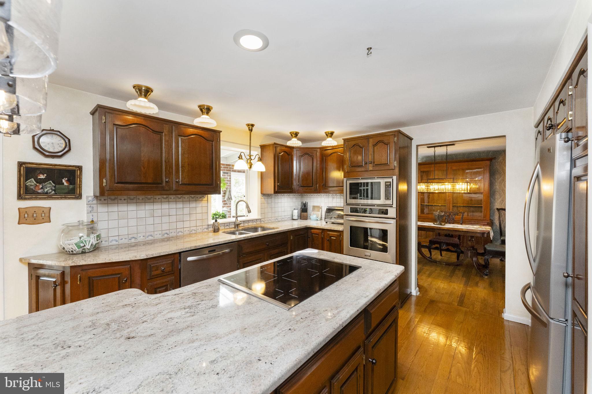 5101 Hiffletrayer Road Green Lane, PA 18054 - Photo 4 of 27 a kitchen with stainless steel appliances granite countertop a sink and stove top oven with wooden floor