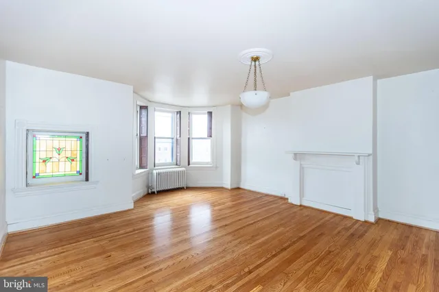 a view of empty room with wooden floor and window