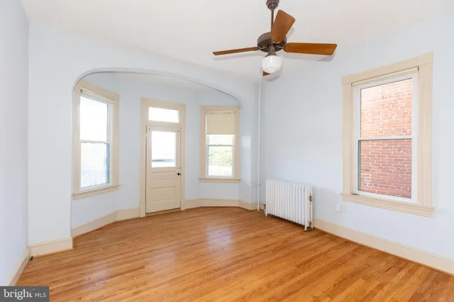 a view of an empty room with a window and wooden floor