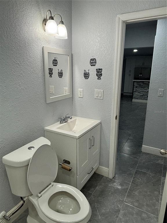 7185 Holiday Drive Spring Hill, FL 34606 - Photo 12 of 25 a bathroom with a toilet a sink and mirror