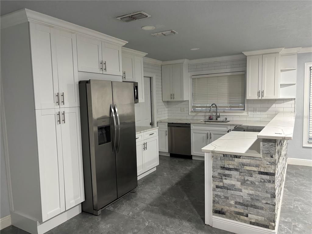 7185 Holiday Drive Spring Hill, FL 34606 - Photo 5 of 25 a kitchen with stainless steel appliances granite countertop a refrigerator sink and cabinets