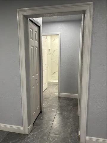 a view of a hallway with a glass door and a bathroom in closet
