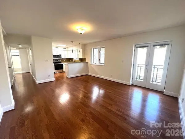 a view of a living room and kitchen with furniture and wooden floor