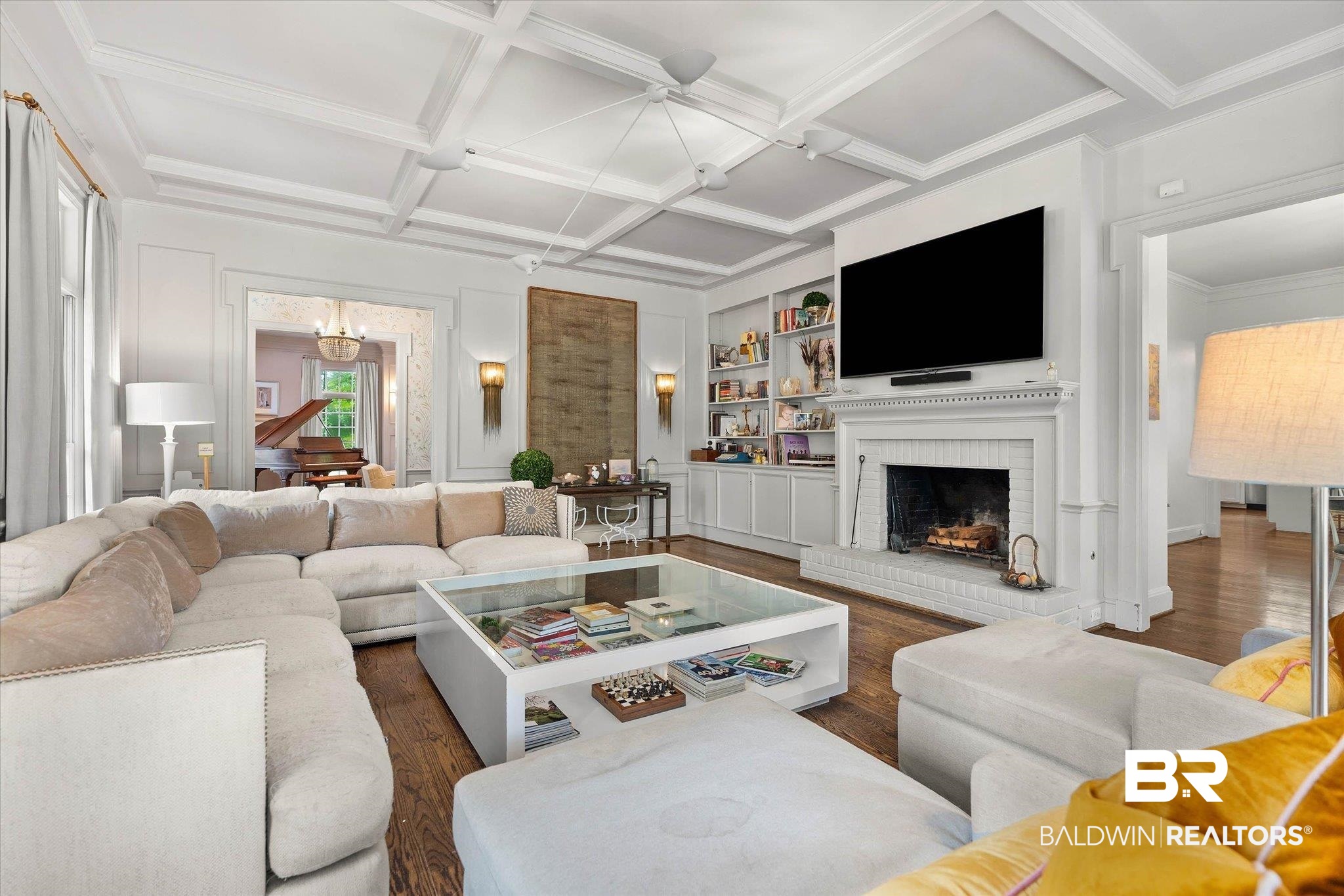 3908 Yester Place Mobile, AL 36608 - Photo 11 of 45 Spacious living area featuring coffered ceilings, dark wood-finish flooring, and a white brick fireplace with a detailed mantel