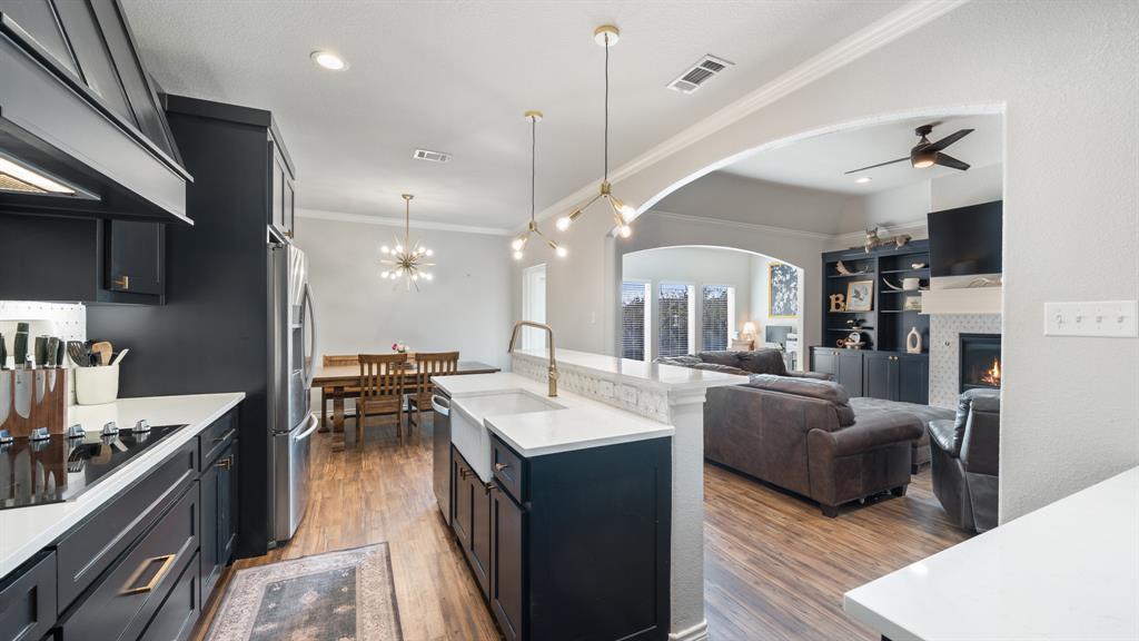101 Lighthouse Lane Mabank, TX 75143 - Photo 13 of 40 Kitchen featuring dark cabinetry, crown molding, stainless steel appliances, a center island with sink, and dark wood finished floors