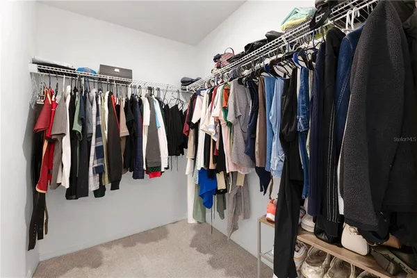 a view of walk in closet with clothes and shoes